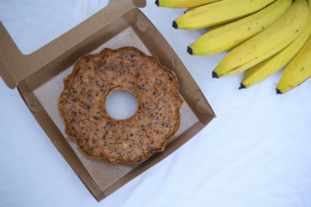 A box with a donut and a bunch of bananas